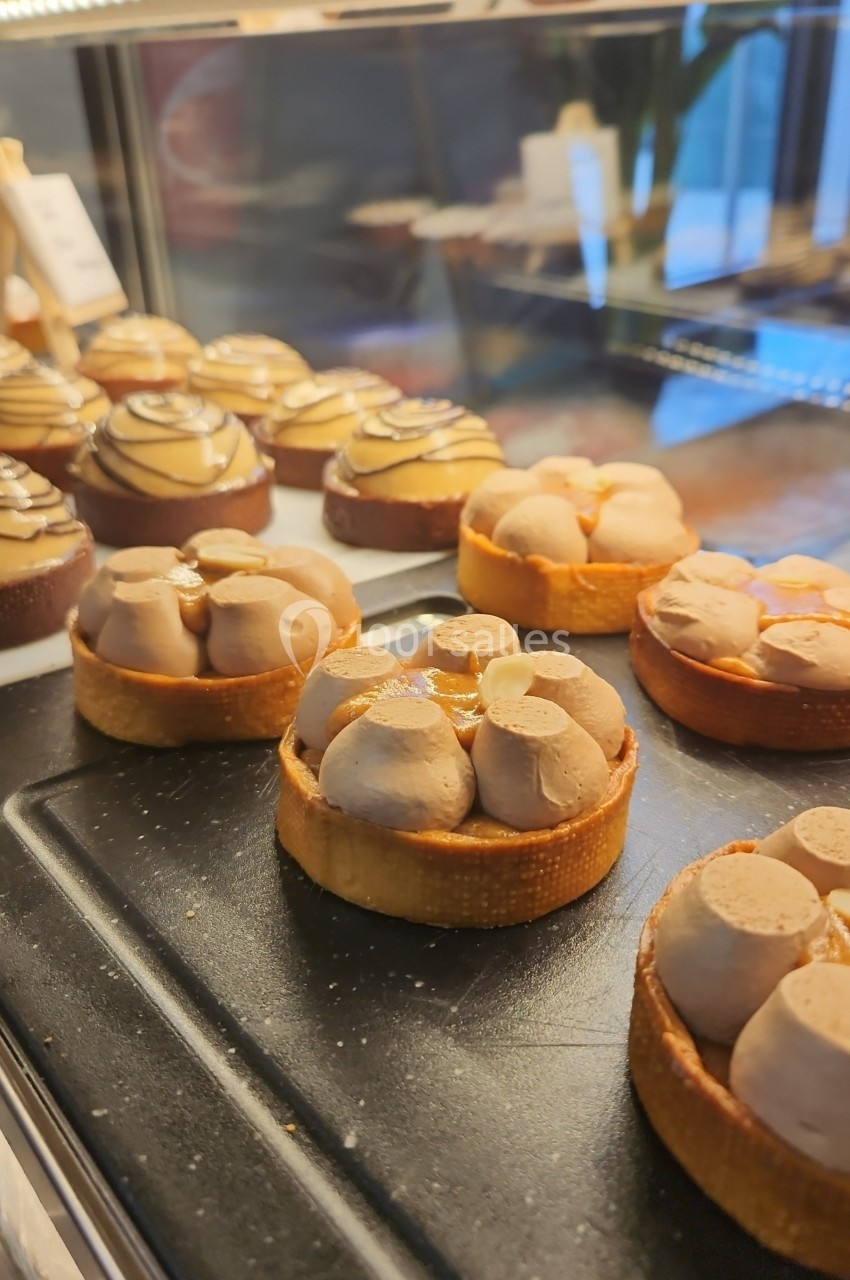 Vitrine de pâtisserie présentant des tartes garnies de crème et de fruits, disposées sur un plateau noir.
