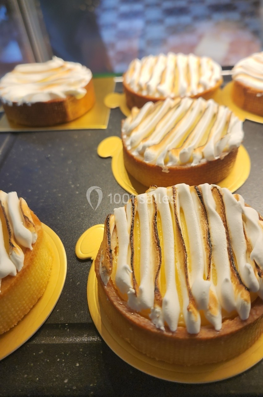 Tartelettes au citron meringuées alignées sur un présentoir, avec une base dorée et une meringue légèrement dorée.