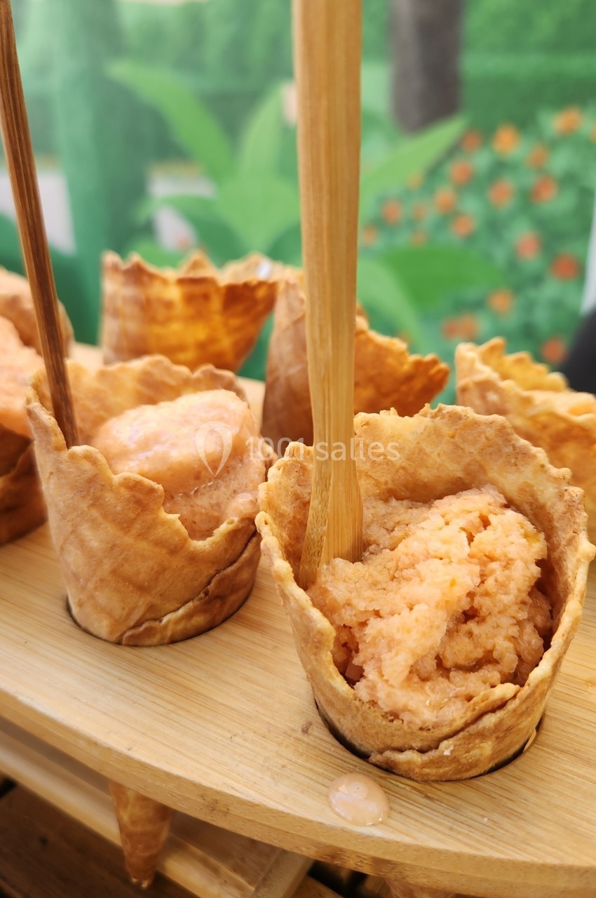 Glaces servies dans des cornets gaufrés avec des cuillères en bois, présentées sur un plateau en bois.