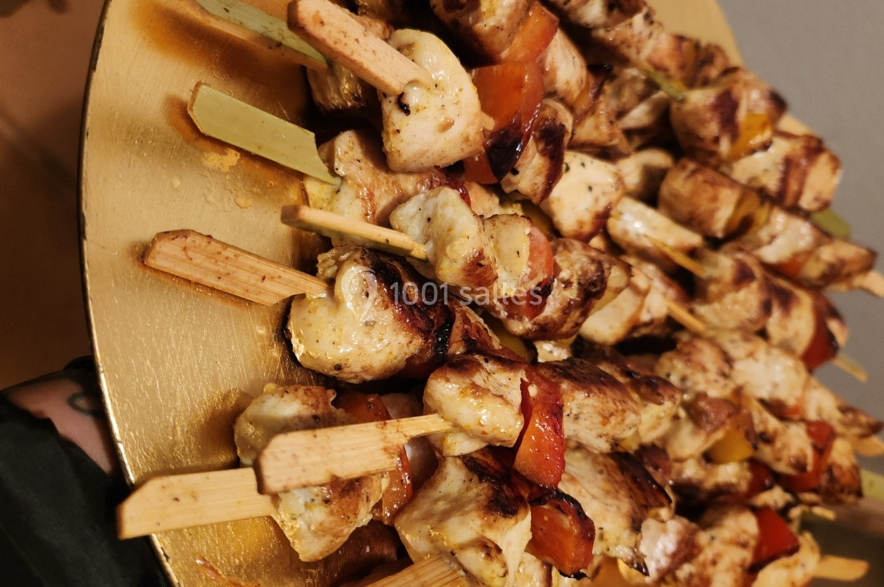Assiette remplie de brochettes de poulet grillé avec des morceaux de poivrons rouges, servies sur des piques en bois.