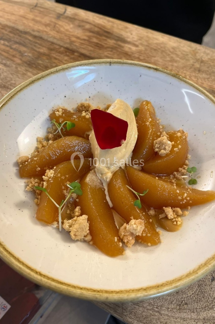 Assiette de poires caramélisées disposées en éventail avec une quenelle de crème et une pétale rouge au centre.