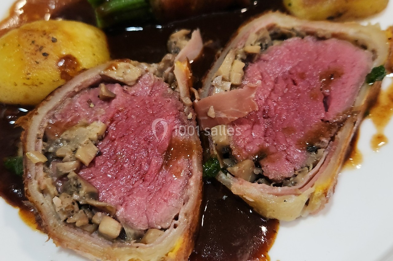 Tranche de filet de bœuf en croûte, garni de champignons, accompagné de pommes de terre et sauce brune.