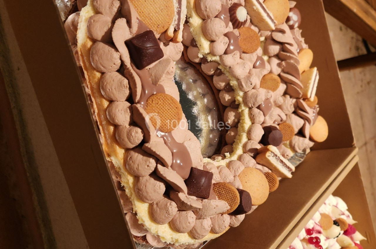 Gâteau en forme de couronne décoré de crème chocolatée, biscuits et morceaux de chocolat.