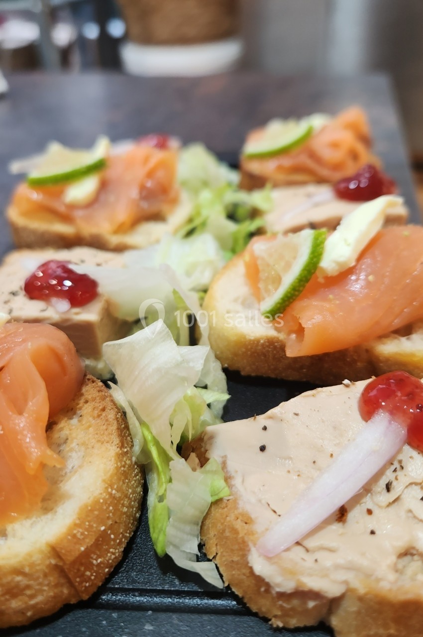 Assortiment de toasts garnis de saumon fumé, foie gras, confiture, citron vert et salade en décoration.