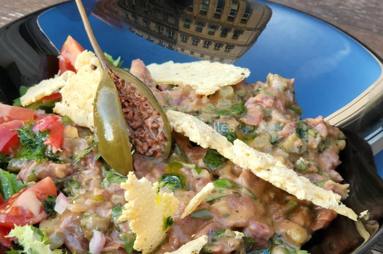 Assiette de guacamole maison avec tomates, herbes fraîches, chips de maïs et une câpre en décoration.
