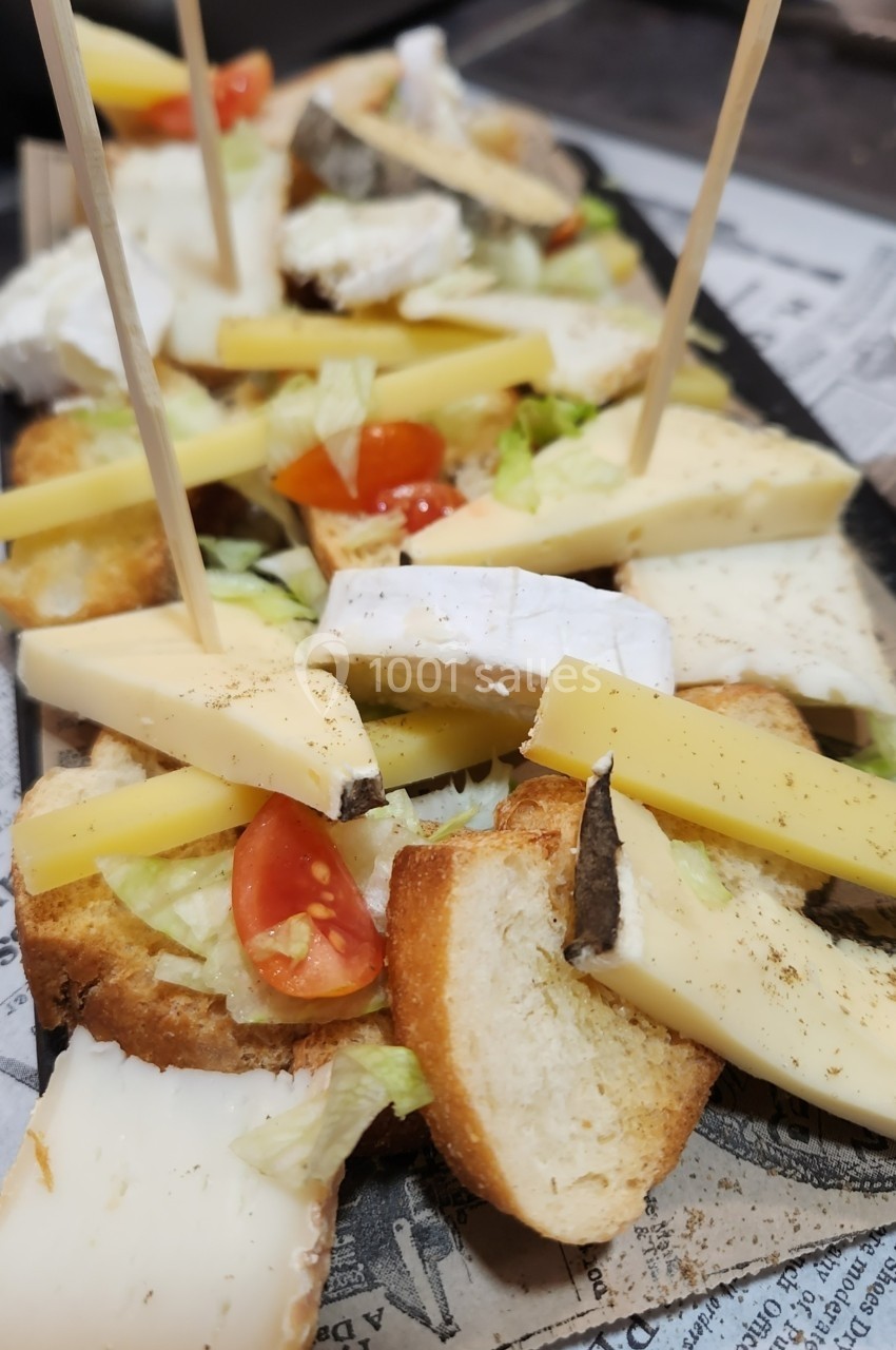 Assortiment de fromages, croûtons, tomates cerises et salade, présenté sur un plateau avec des piques en bois.