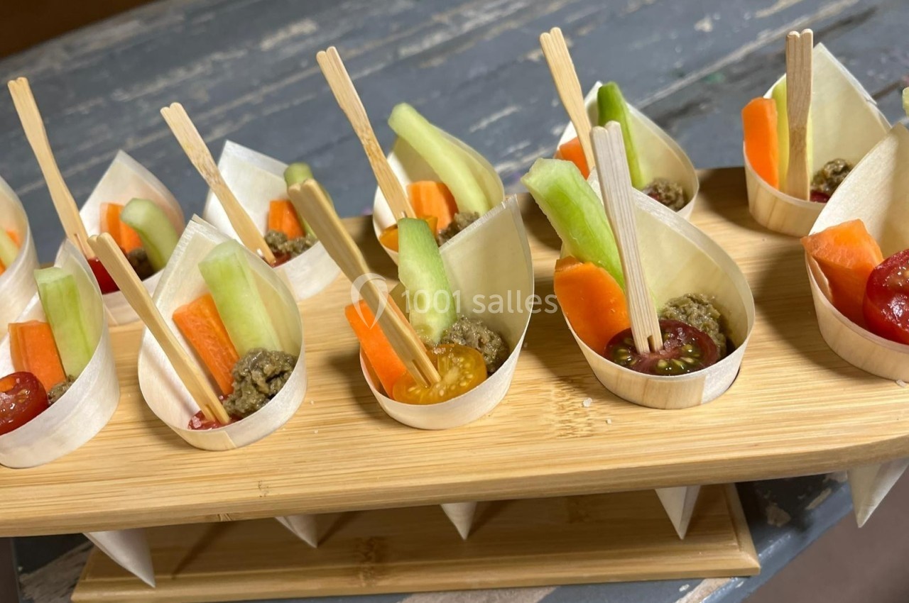 Coupelles en bois contenant des bâtonnets de légumes frais et des sauces, présentées sur un support en bois.