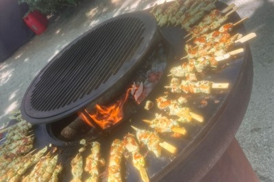 Illustration de deux oliviers entourant des tables et chaises disposées en extérieur, décorées de guirlandes lumineuses.