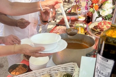 Illustration de deux oliviers entourant des tables et chaises disposées en extérieur, décorées de guirlandes lumineuses.