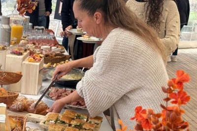 Illustration de deux oliviers entourant des tables et chaises disposées en extérieur, décorées de guirlandes lumineuses.