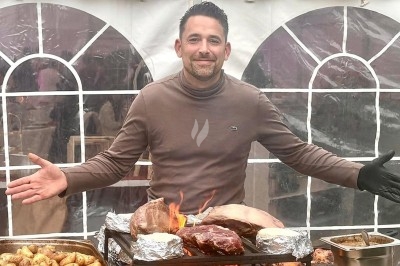 Des invités assis à des tables décorées de fleurs et feuillages d'automne dans une grande tente lumineuse.