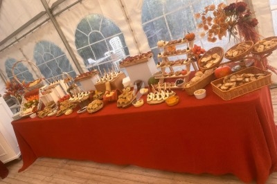 Des invités assis à des tables décorées de fleurs et feuillages d'automne dans une grande tente lumineuse.