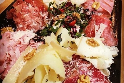 Des invités assis à des tables décorées de fleurs et feuillages d'automne dans une grande tente lumineuse.