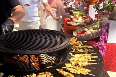 Des invités assis à des tables décorées de fleurs et feuillages d'automne dans une grande tente lumineuse.