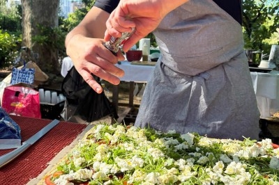 Des invités assis à des tables décorées de fleurs et feuillages d'automne dans une grande tente lumineuse.