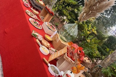 Des invités assis à des tables décorées de fleurs et feuillages d'automne dans une grande tente lumineuse.