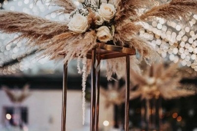 Des invités assis à des tables décorées de fleurs et feuillages d'automne dans une grande tente lumineuse.