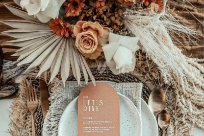 Des invités assis à des tables décorées de fleurs et feuillages d'automne dans une grande tente lumineuse.