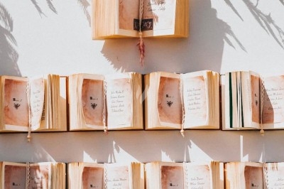 Des invités assis à des tables décorées de fleurs et feuillages d'automne dans une grande tente lumineuse.