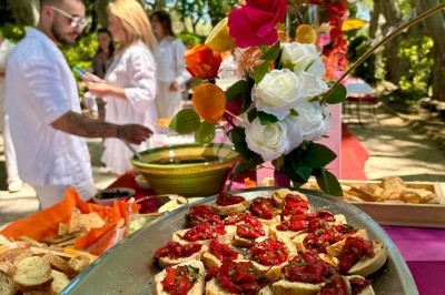 Des invités assis à des tables décorées de fleurs et feuillages d'automne dans une grande tente lumineuse.