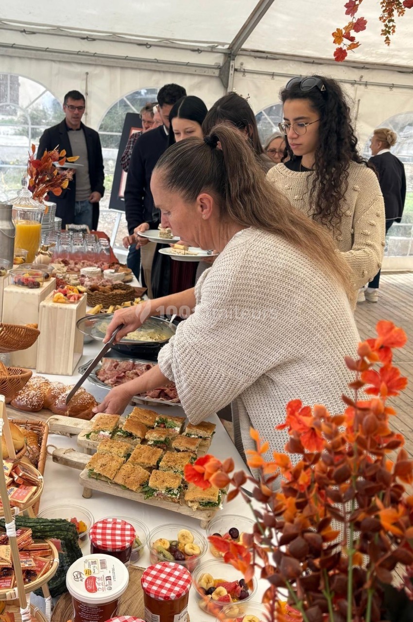 Personnes se servant à un buffet varié sous une tente, décorée avec des éléments automnaux.