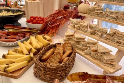Des invités assis à des tables décorées de fleurs et feuillages d'automne dans une grande tente lumineuse.