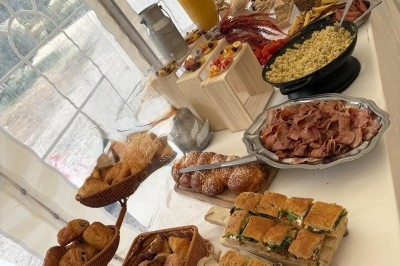 Des invités assis à des tables décorées de fleurs et feuillages d'automne dans une grande tente lumineuse.