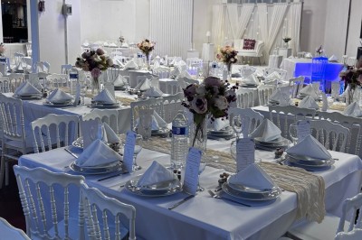 Tables de pique-nique en bois sur une terrasse en béton, entourées de pelouse et d'arbres sous un ciel nuageux.