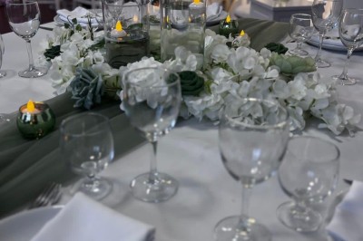 Tables de pique-nique en bois sur une terrasse en béton, entourées de pelouse et d'arbres sous un ciel nuageux.
