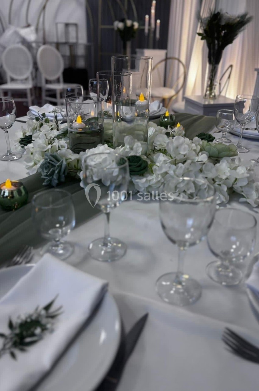 Décoration de table élégante avec fleurs blanches, bougies LED et vaisselle disposée pour un repas formel.