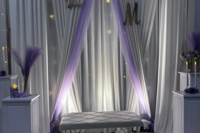 Tables de pique-nique en bois sur une terrasse en béton, entourées de pelouse et d'arbres sous un ciel nuageux.