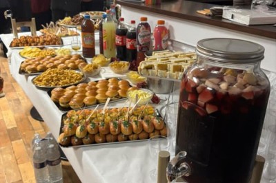 Tables de pique-nique en bois sur une terrasse en béton, entourées de pelouse et d'arbres sous un ciel nuageux.