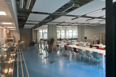 Bâtiment moderne avec façades vitrées, espaces verts et escaliers extérieurs dans un environnement urbain.