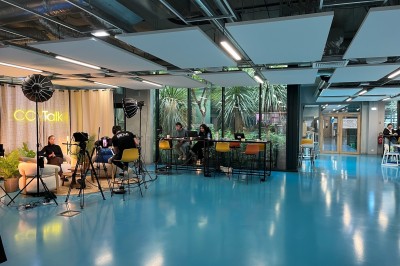 Bâtiment moderne avec façades vitrées, espaces verts et escaliers extérieurs dans un environnement urbain.