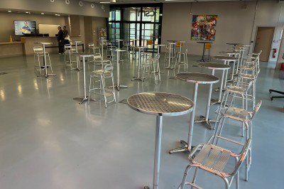 Bâtiment moderne avec façades vitrées, espaces verts et escaliers extérieurs dans un environnement urbain.