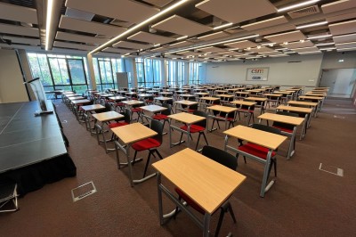 Bâtiment moderne avec façades vitrées, espaces verts et escaliers extérieurs dans un environnement urbain.