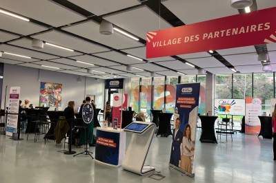 Bâtiment moderne avec façades vitrées, espaces verts et escaliers extérieurs dans un environnement urbain.