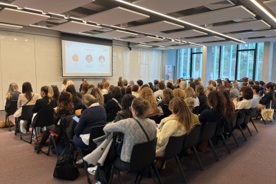 Bâtiment moderne avec façades vitrées, espaces verts et escaliers extérieurs dans un environnement urbain.