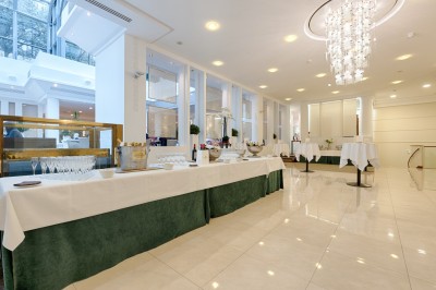 Buffet de petit-déjeuner avec viennoiseries, fromages, charcuterie, pain et confitures, dans une salle lumineuse.