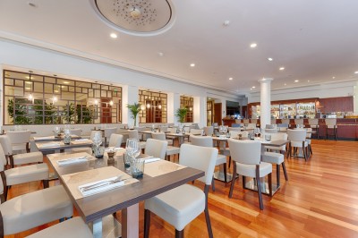 Buffet de petit-déjeuner avec viennoiseries, fromages, charcuterie, pain et confitures, dans une salle lumineuse.