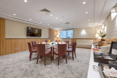 Buffet de petit-déjeuner avec viennoiseries, fromages, charcuterie, pain et confitures, dans une salle lumineuse.