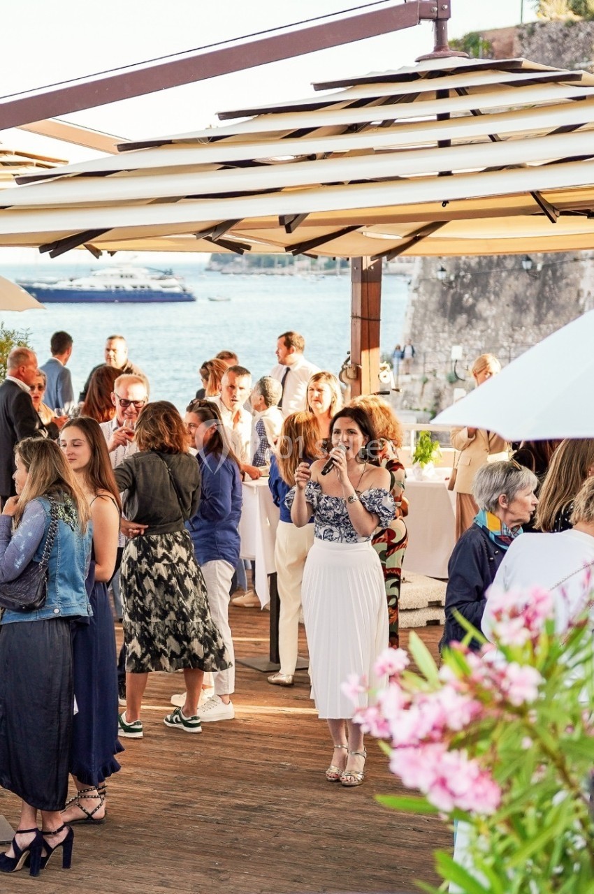 Groupe de personnes discutant et prenant des photos lors d'un événement en plein air près de l'eau.