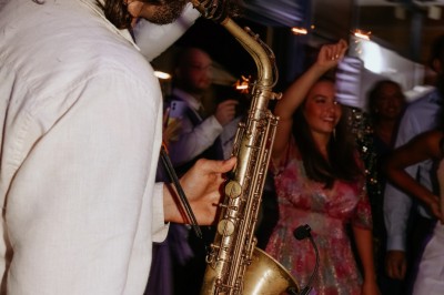 Terrasse en bord de mer avec tables dressées, chaises en osier et parasols sous un ciel ensoleillé.