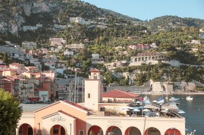 Un verre à cocktail garni d'un demi-fruit de la passion, posé sur une table dressée en extérieur.