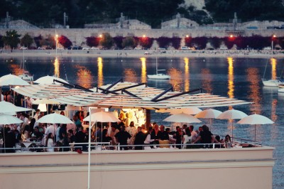 Un verre à cocktail garni d'un demi-fruit de la passion, posé sur une table dressée en extérieur.