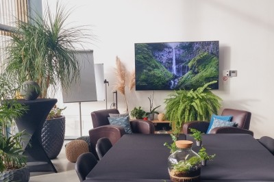 Façade d'une maison moderne en bois et verre, éclairée de nuit, avec jardin et portail en premier plan.