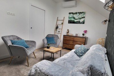 Façade d'une maison moderne en bois et verre, éclairée de nuit, avec jardin et portail en premier plan.