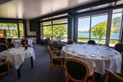 Chambre d'hôtel avec lit double, bureau, lampe, télévision murale et fenêtre donnant sur un paysage verdoyant.