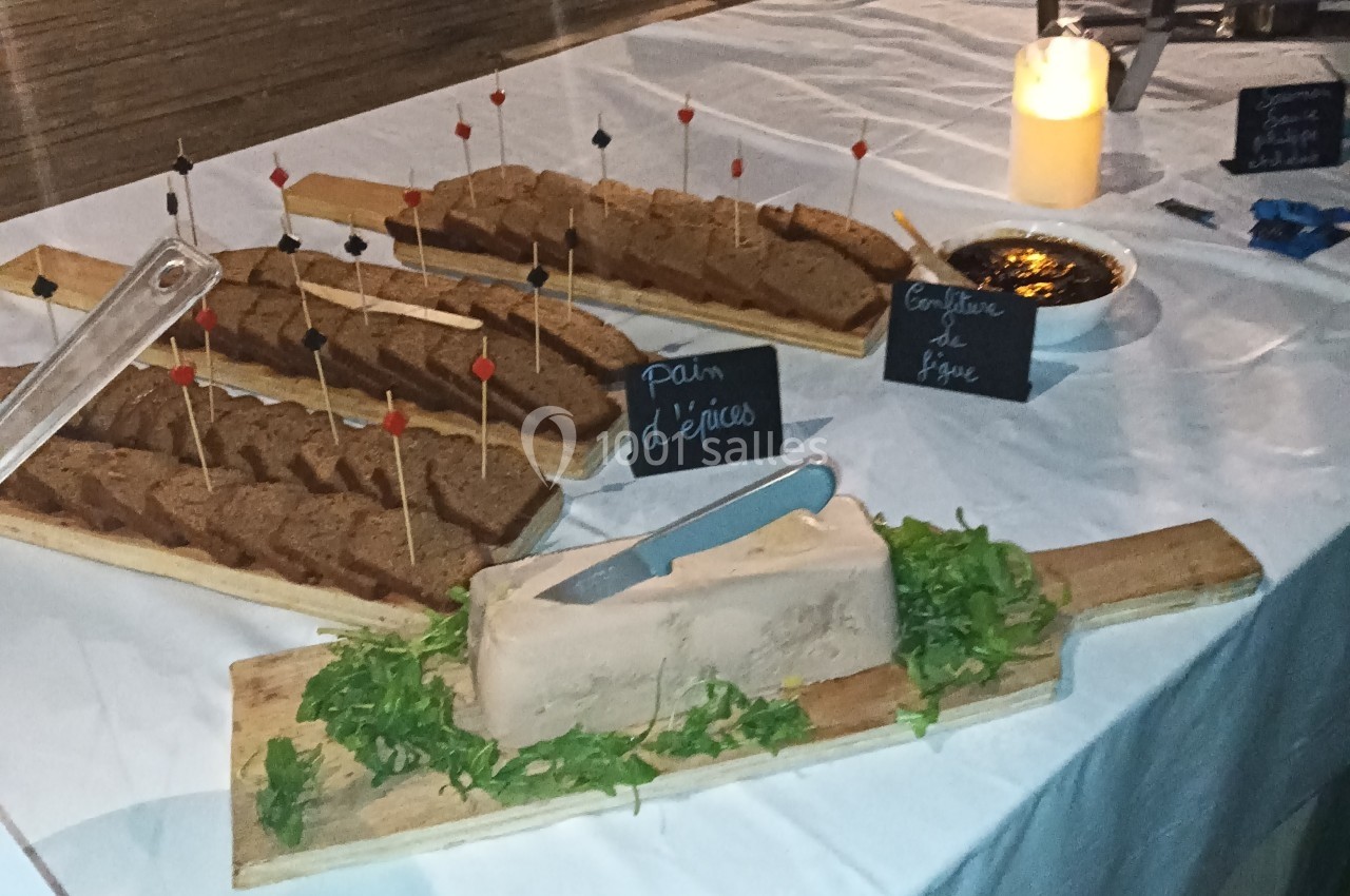 Plateau de foie gras sur lit de roquette, accompagné de pain d'épices et de confiture de figue sur une table dressée.