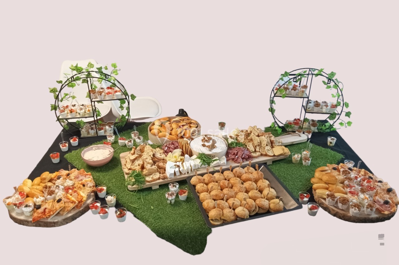 Buffet varié avec pâtisseries, charcuteries, pains et verrines, disposé sur une table décorée de verdure.